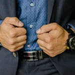 Seorang pebisnis rapi merapikan jaket setelannya sebagai ilustrasi grooming profesional di dunia kerja